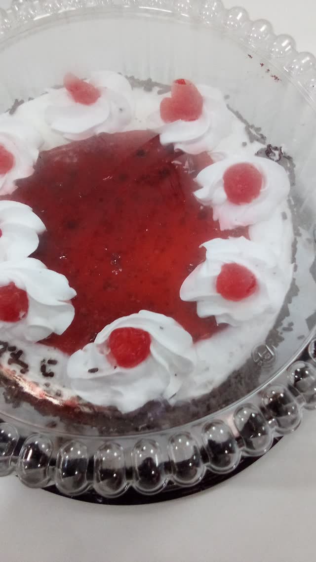 Close-up of a delivered cake with white cream and cherries in a clear container
